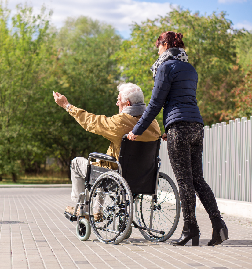 A support worker assists an older man in a wheelchair outdoors, symbolising YWECARE’s NDIS daily living support services in Sydney.